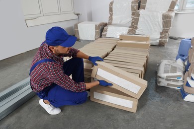 Construction worker with packed new boxes in room prepared for renovation