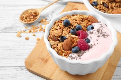 Photo of Tasty homemade granola served on white wooden table. Healthy breakfast