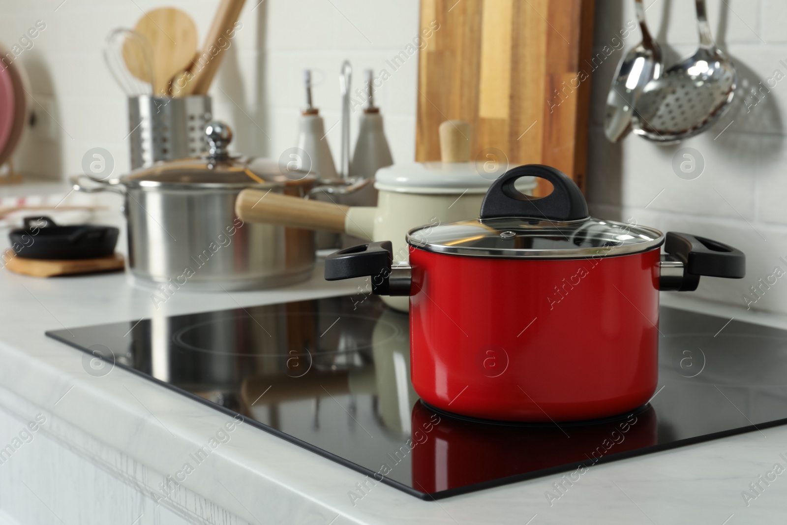 Photo of Red pot on electric stove in kitchen. Cooking utensil