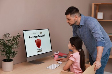 Photo of Dad installing parental control on computer at table indoors. Child safety