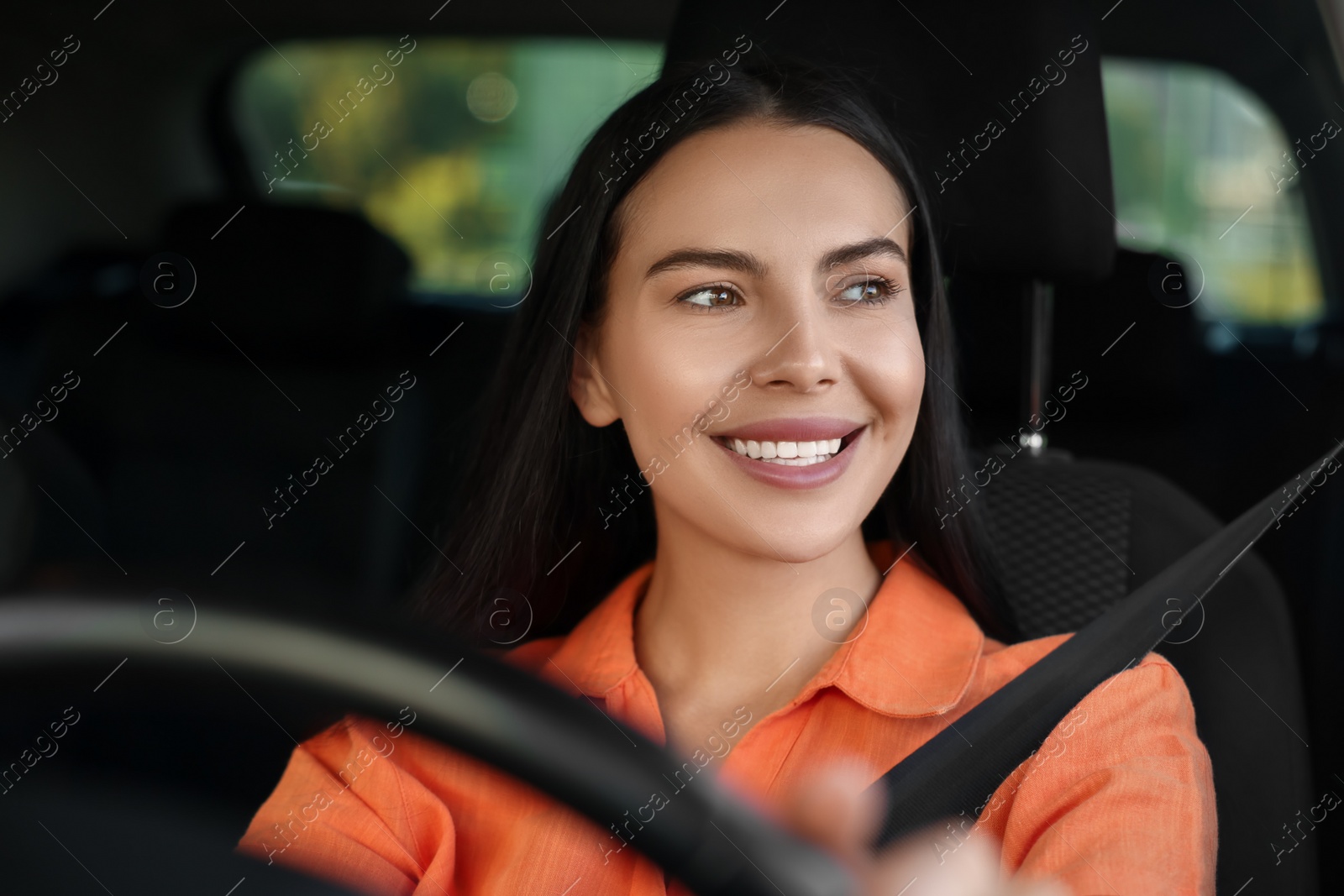 Photo of Enjoying trip. Happy young woman driving her car, view through windshield