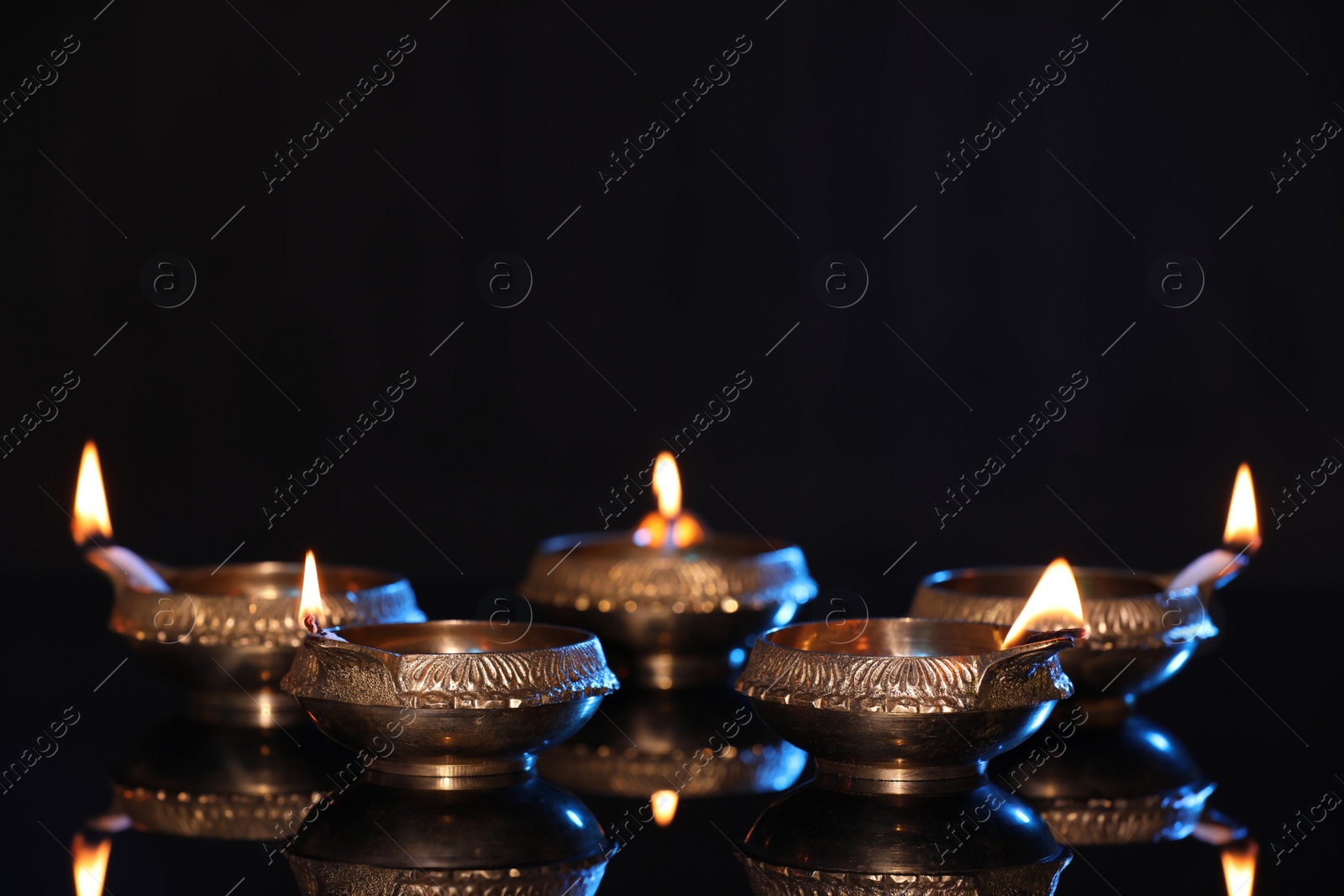 Photo of Many lit diyas on black background, space for text. Diwali lamps