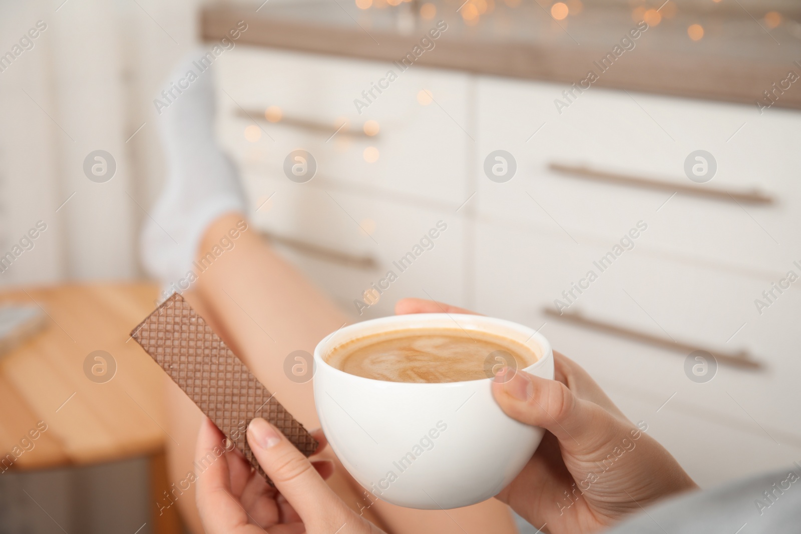 Photo of Woman having delicious wafer and coffee for breakfast indoors, closeup