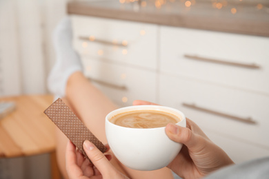 Woman having delicious wafer and coffee for breakfast indoors, closeup