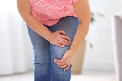 Photo of Senior woman suffering from knee pain at home, closeup