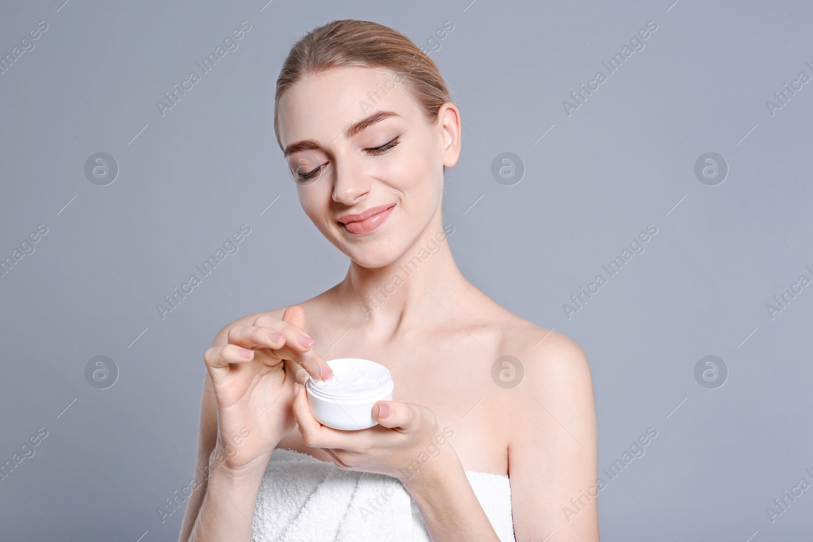 Photo of Young woman with jar of body cream on color background