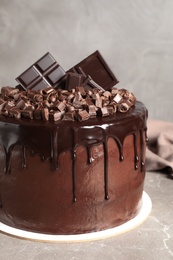 Photo of Freshly made delicious chocolate cake on marble table against grey background