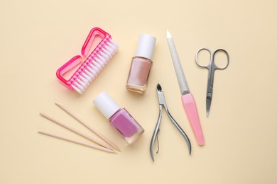 Set of pedicure tools on beige background, flat lay