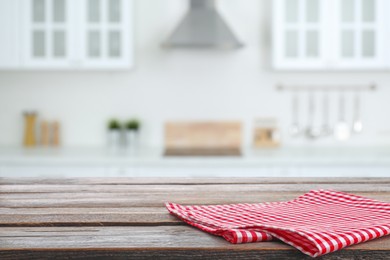 Image of Red checkered napkin on wooden table and blurred view of stylish kitchen interior. Space for design