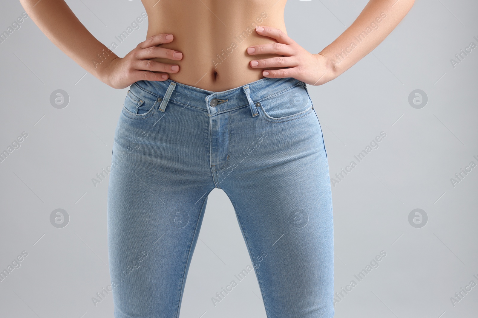 Photo of Woman wearing stylish jeans on light gray background, closeup