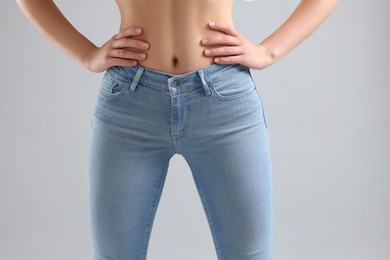 Photo of Woman wearing stylish jeans on light gray background, closeup