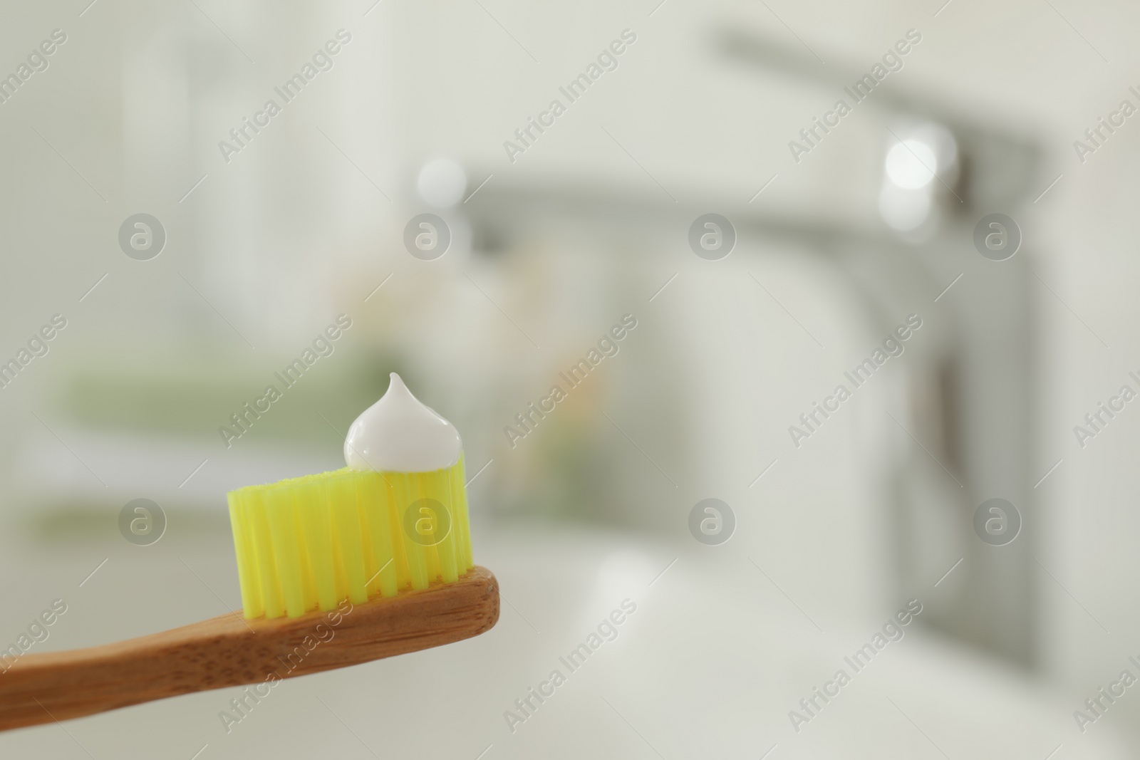 Photo of Brush with toothpaste in bathroom, closeup. Space for text