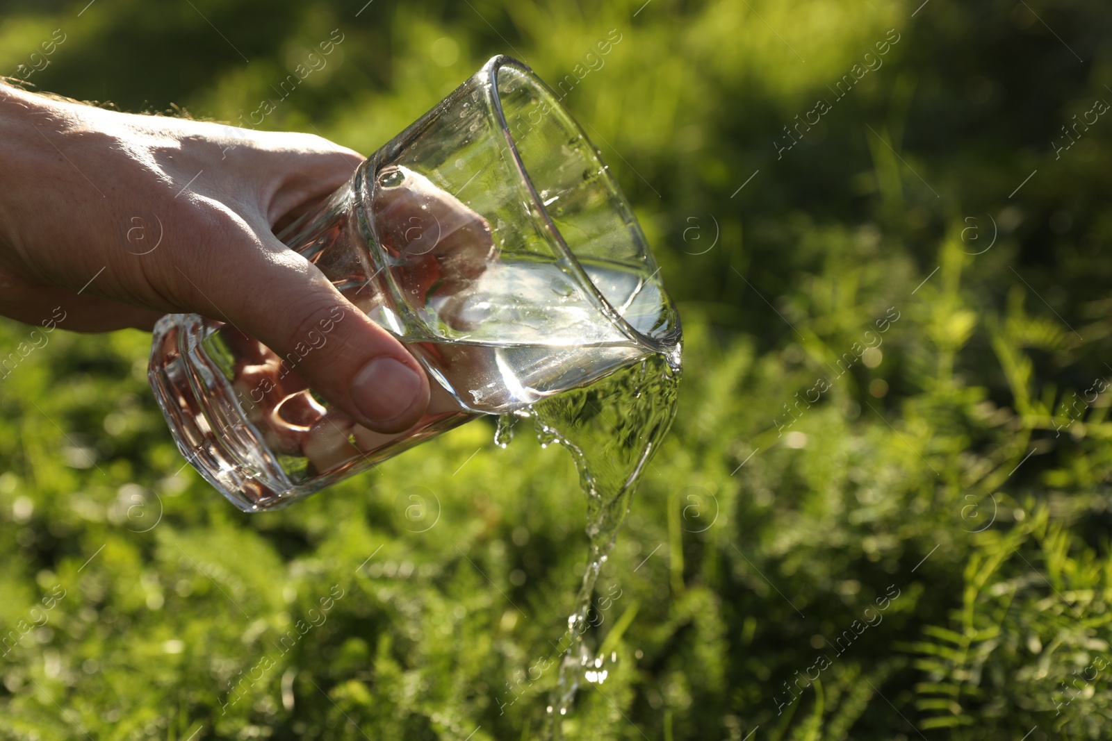 Photo of Man pouring fresh water from glass outdoors, closeup