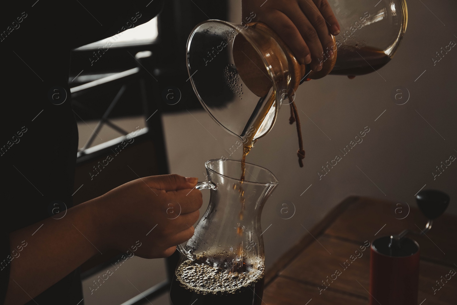 Photo of Barista pouring coffee into glass jug in cafe, closeup