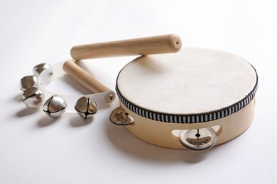 Photo of Wooden tambourine, rhythm stick and hand bells on white background. Montessori musical toy