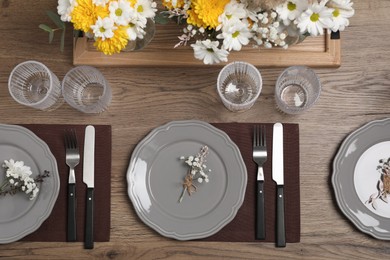 Photo of Elegant festive setting with floral decor on wooden table, flat lay