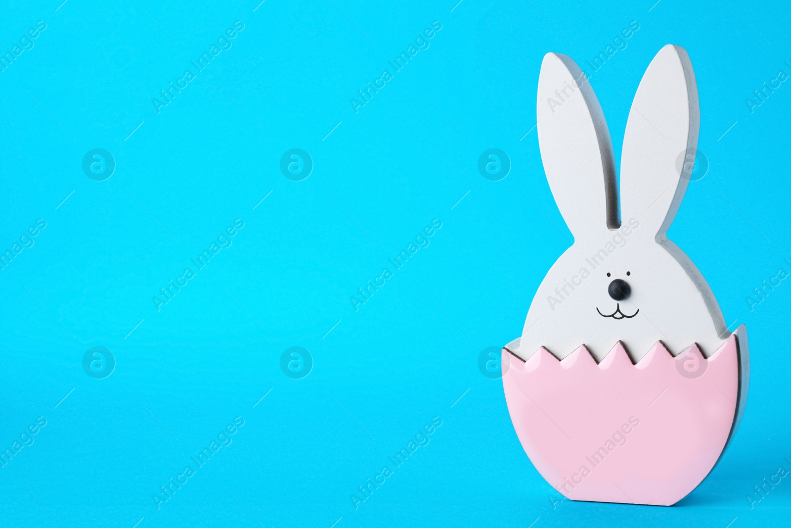 Photo of Bunny figure as Easter decor on blue background. Space for text