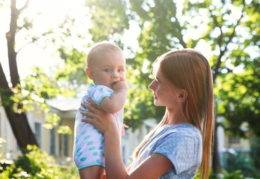 Teen nanny with cute baby outdoors on sunny day