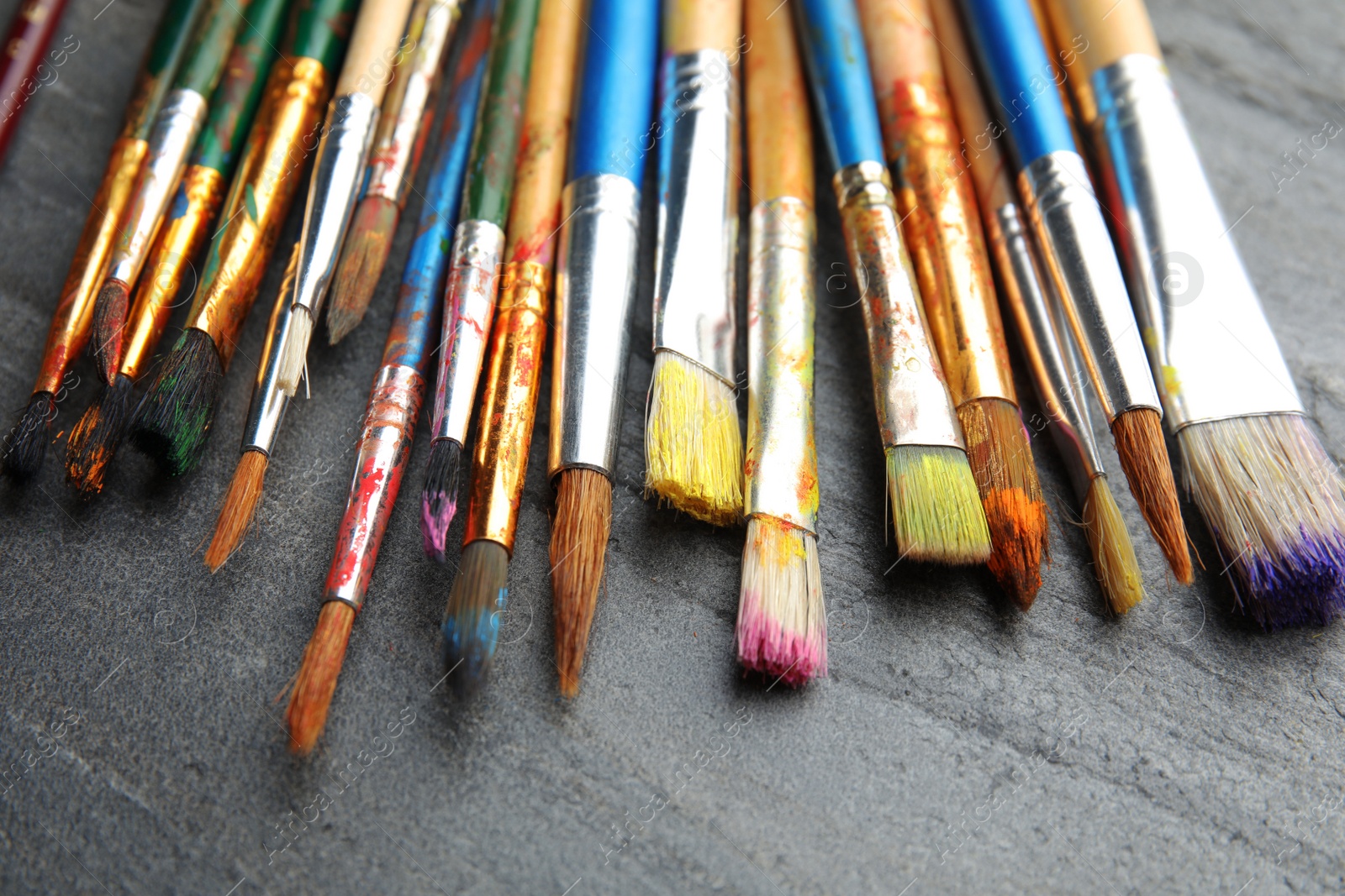 Photo of Different paint brushes on grey table, closeup