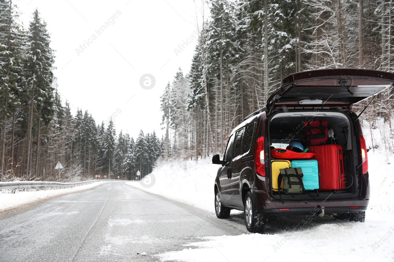 Photo of Car with open trunk full of luggage near road, space for text. Winter vacation