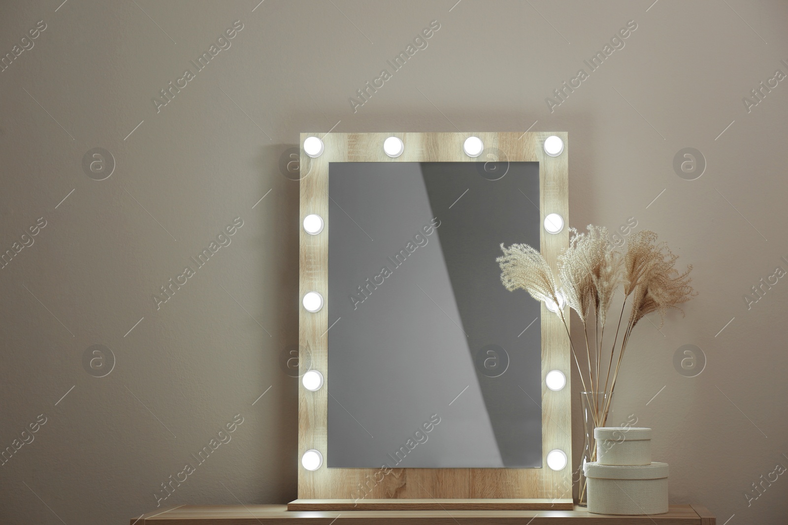 Photo of Modern mirror with lamps near beige wall in room