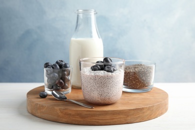 Tasty chia seed pudding with blueberries and ingredients on table