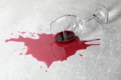 Overturned glass with red wine spill on grey table