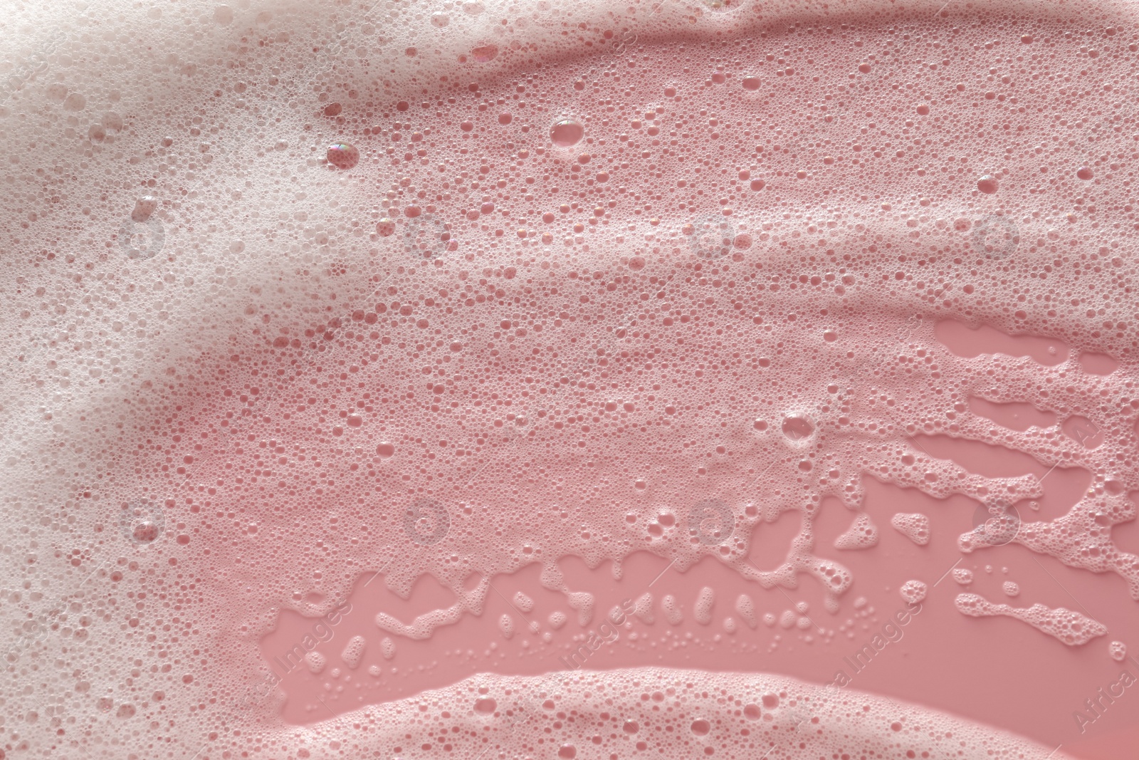 Photo of White washing foam on pale pink background, top view