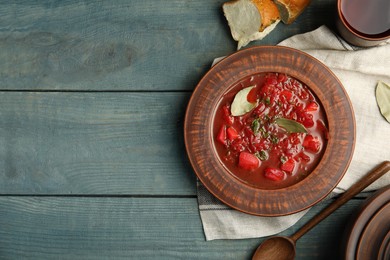 Photo of Stylish brown clay plate with Ukrainian borsch served  on wooden table, flat lay. Space for text