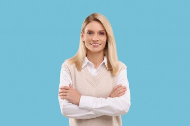 Photo of Portrait of smiling middle aged woman with crossed arms on light blue background