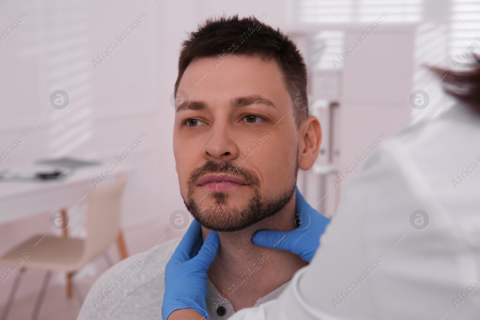 Photo of Doctor examining thyroid gland of patient in hospital