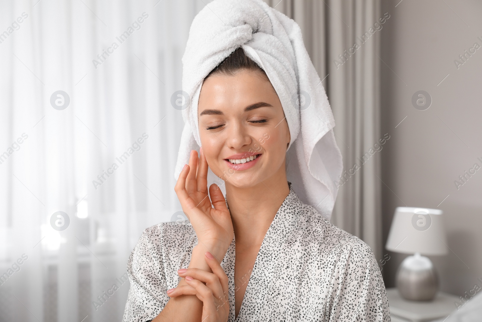 Photo of Beautiful young woman with hair wrapped in towel at home