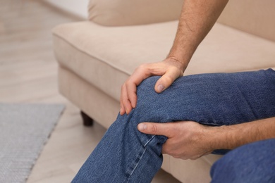 Photo of Senior man suffering from knee pain at home,closeup. Space for text