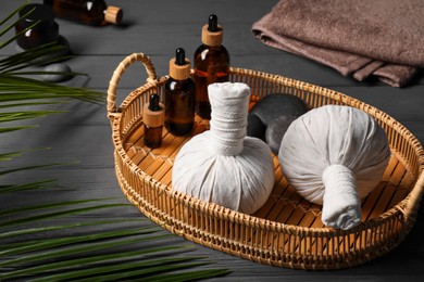 Photo of Herbal massage bags, essential oils and spa stones on grey wooden table