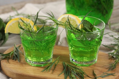 Photo of Glasses of refreshing tarragon drink with lemon slices on tablecloth