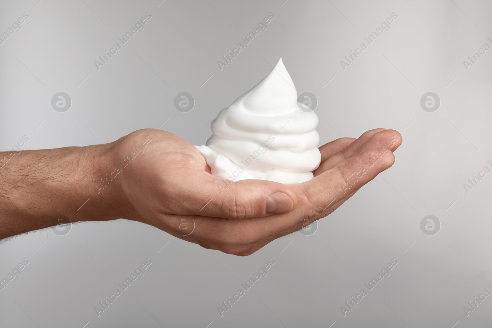 Photo of Man holding shaving foam on light grey background, closeup