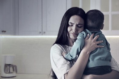 Image of Depressed single mother with child at home, color toned