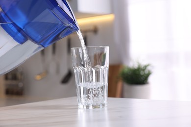 Photo of Pouring water from filter jug into glass in kitchen, closeup