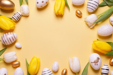 Photo of Frame of painted Easter eggs and tulip flowers on yellow background, flat lay. Space for text