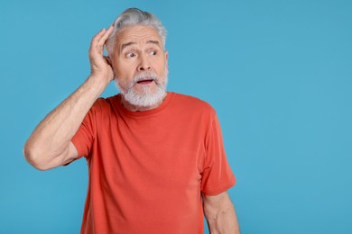 Photo of Portrait of surprised senior man on light blue background, space for text