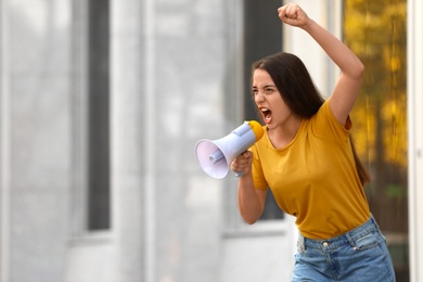 Emotional young woman with megaphone outdoors. Protest leader