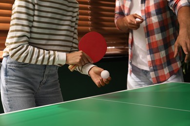 Photo of Woman playing ping pong with friend indoors, closeup