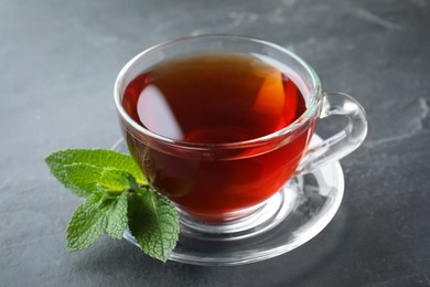 Photo of Cup of hot aromatic tea with mint on grey table