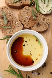 Bowl of organic balsamic vinegar with oil, bread slices and spices on wooden board, flat lay