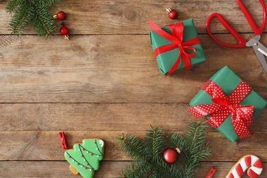 Flat lay composition with Christmas gift boxes, decor and gingerbreads on wooden table, space for text