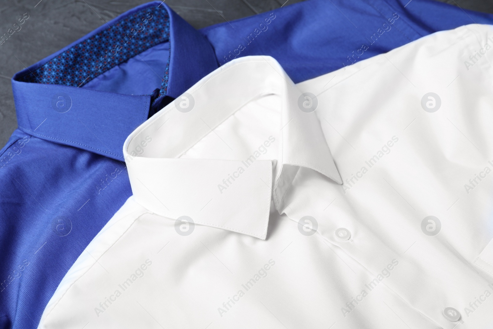 Photo of Stylish shirts on grey table, closeup. Dry-cleaning service