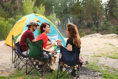 Photo of Young people having lunch with sausages near camping tent outdoors