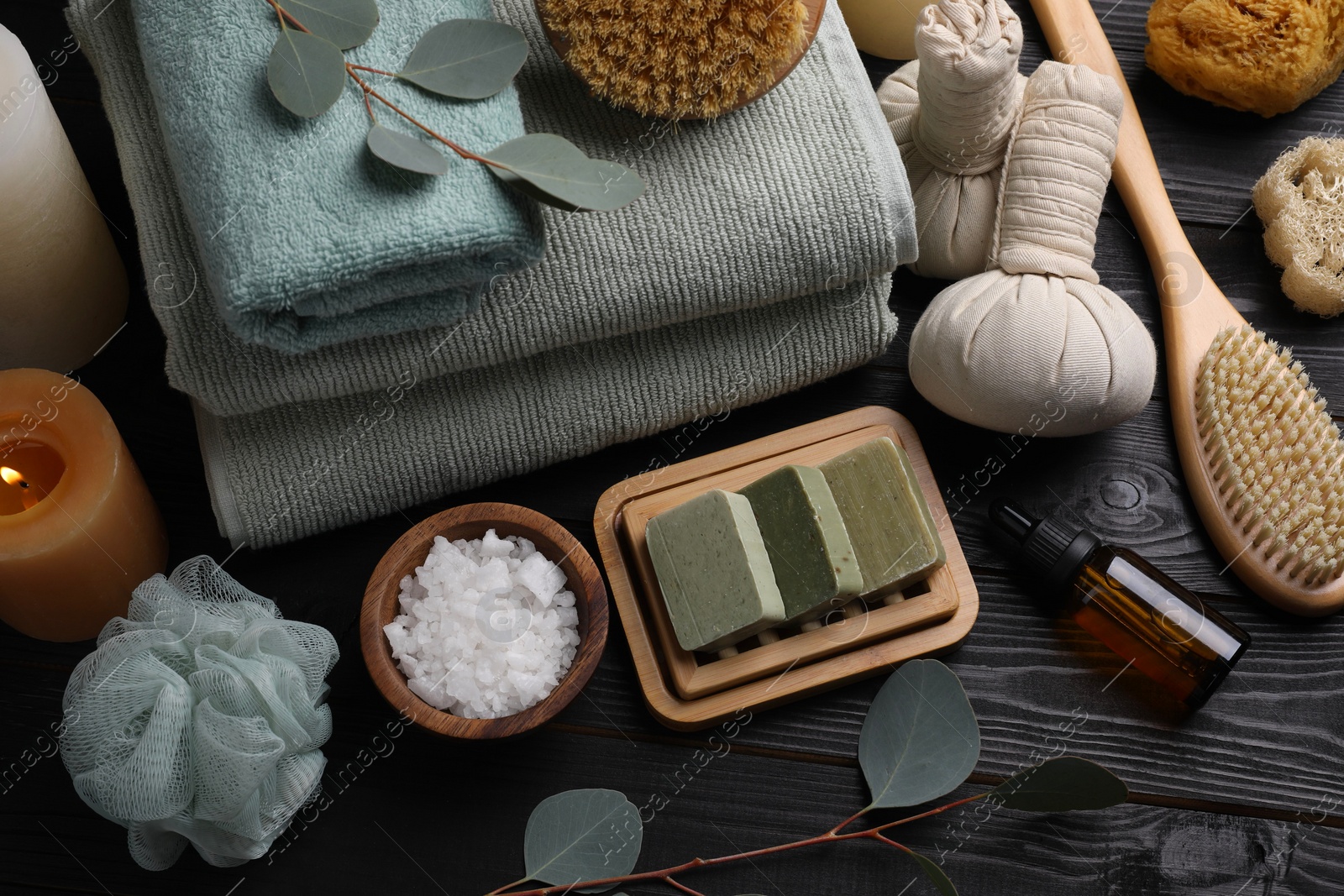 Photo of Composition with different spa products and eucalyptus branches on black wooden table, above view