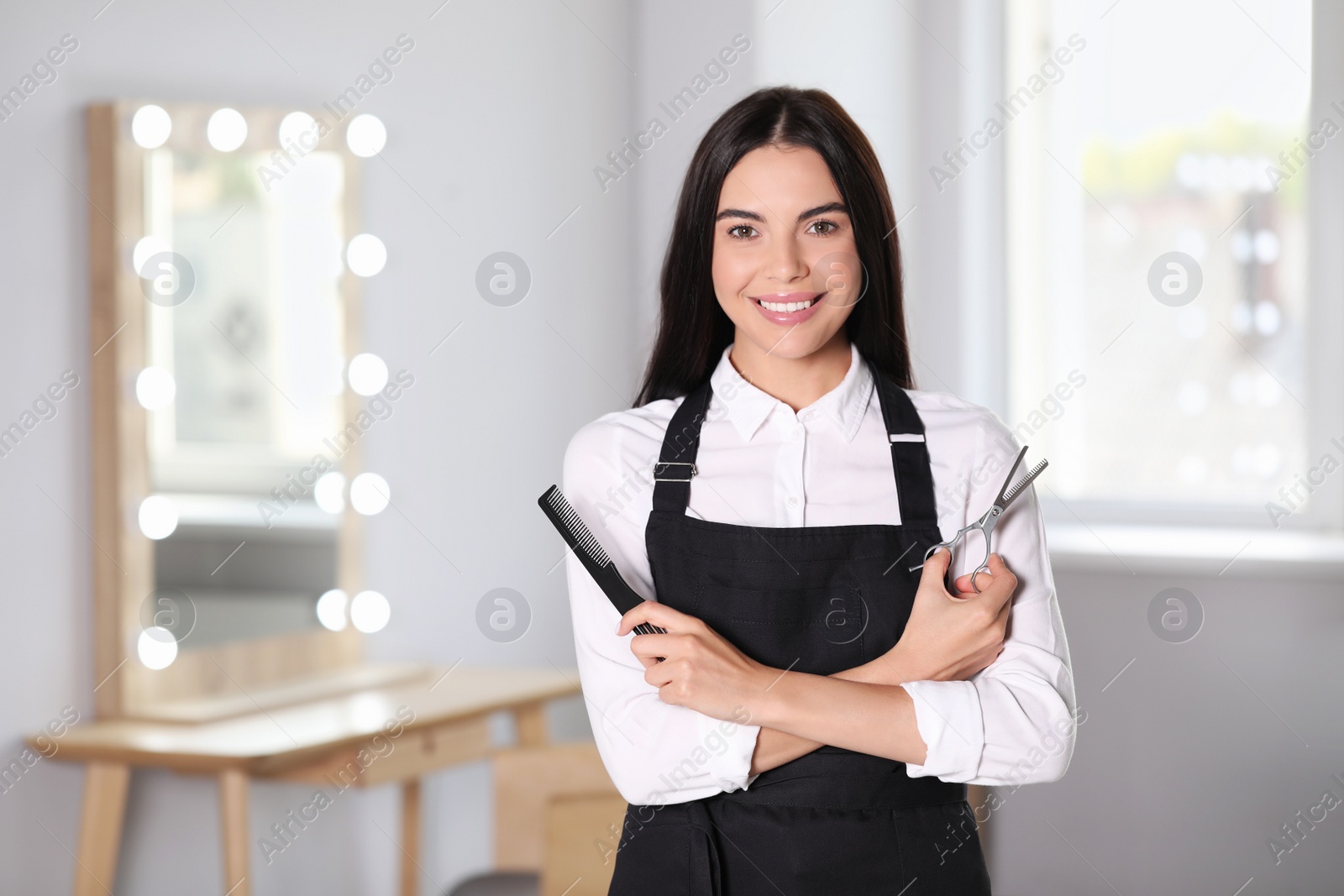 Photo of Portrait of happy hairdresser with professional tools in beauty salon, space for text
