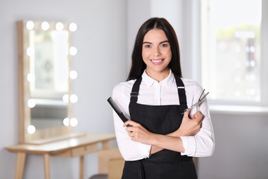 Portrait of happy hairdresser with professional tools in beauty salon, space for text